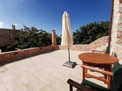a patio with an umbrella and a table and a chair at Guesthouse Toxotis in Pirgos Dhirou