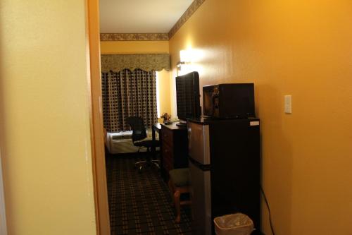 a hotel room with a television and a desk in a room at Magnolia Inn and Suites Southaven in Southaven