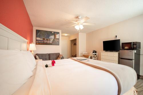 a bedroom with a large white bed and a flat screen tv at Island Sun Inn & Suites - Venice, Florida Historic Downtown & Beach Getaway in Venice