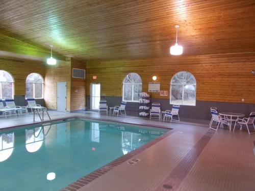 a swimming pool in a building with chairs and tables at Northwoods Best Inn - Chetek in Chetek