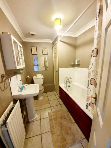 a bathroom with a tub and a sink and a toilet at Chelmsford Town Centre Apartments With Car Parking in Chelmsford