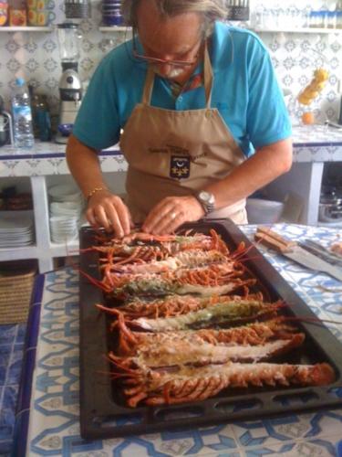 a woman in an apron preparing a tray of food at Villa Daba in Ghazoua