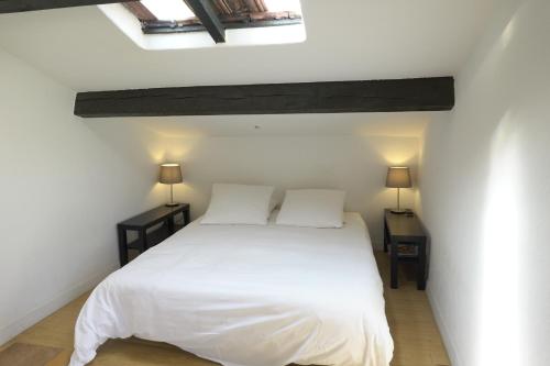 1 dormitorio con 1 cama blanca y 2 mesitas de noche en Le Cigalon, en Grasse