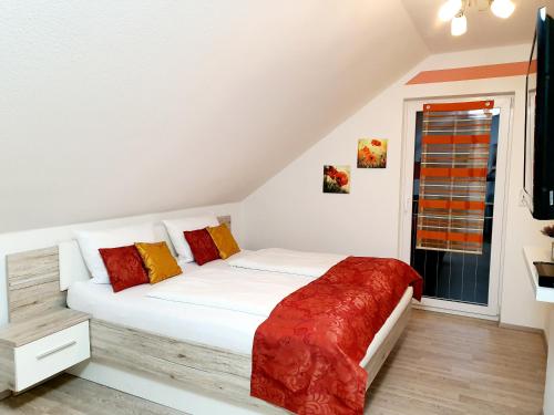 a bedroom with a white bed with red and yellow pillows at Kempf Apartments in Rust