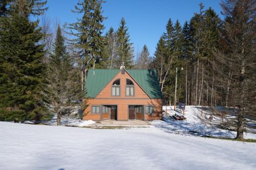 an orange house with a green roof in the snow at Ski in/out Spruce Glen Townhomes on Great Eastern Trail in Killington