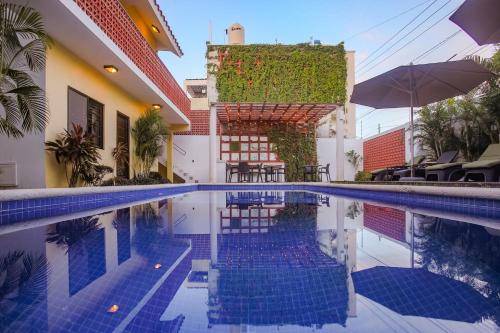 a swimming pool next to a building with an umbrella at Condominio Sac Ki in Cozumel