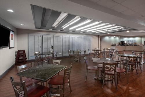 a restaurant with tables and chairs in a room at Wingate by Wyndham Oklahoma City Airport in Oklahoma City