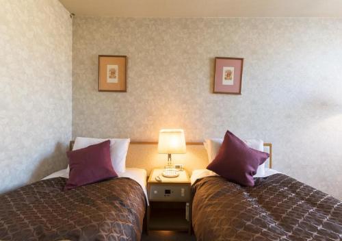 two beds in a hotel room with purple pillows at skyhotel uozu / Vacation STAY 59597 in Uozu