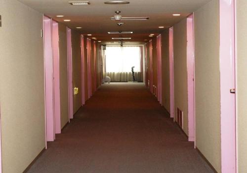 a long hallway with pink and white walls and a window at skyhotel uozu / Vacation STAY 59581 in Uozu