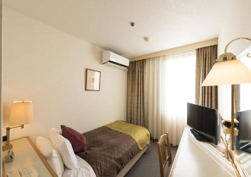 魚津市にあるskyhotel uozu / Vacation STAY 59577のベッドとデスクが備わるホテルルームです。