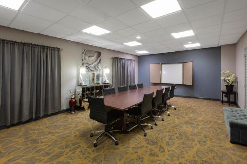 a conference room with a table and chairs and a screen at Wingate by Wyndham Oklahoma City Airport in Oklahoma City
