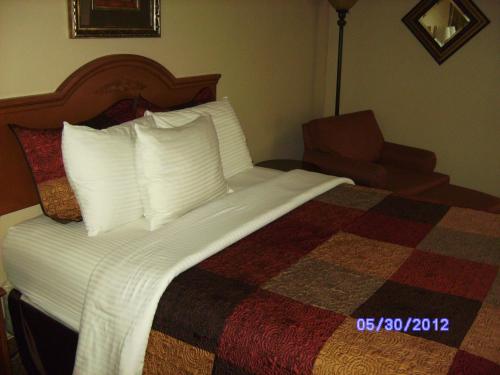 a bed with white pillows and a chair in a hotel room at All American Inn & Suites Branson in Branson