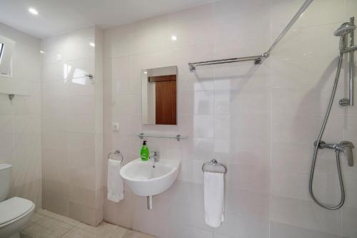 Un baño blanco con lavabo y ducha. en Villa Amelia, en Caniço