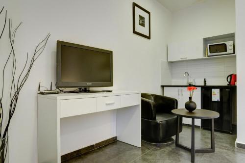 a living room with a television on a white desk at Geula Suites BY RAPHAEL HOTELS in Tel Aviv