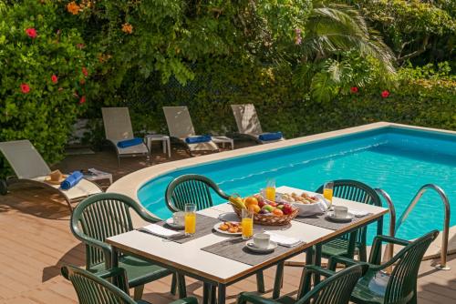 a table with a bowl of fruit next to a swimming pool at Villa Amelia in Caniço
