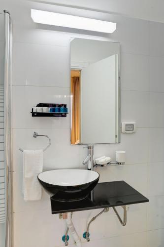 a bathroom with a sink and a mirror at Geula Suites BY RAPHAEL HOTELS in Tel Aviv