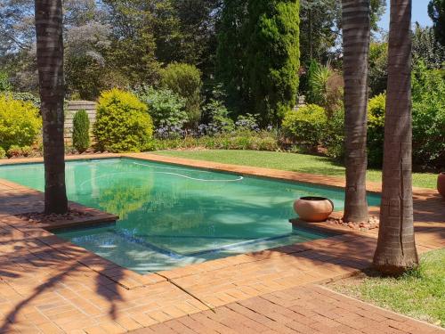 a swimming pool with palm trees in a yard at Accommodation@Bourne in Centurion