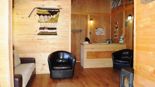 a living room with two leather chairs and a couch at Posada de Expediciones Kahuel in Chaitén