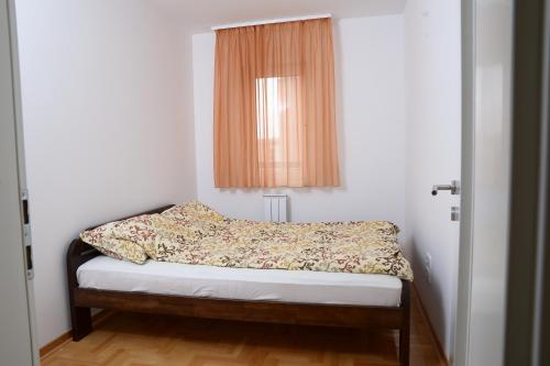 um pequeno quarto com uma cama e uma janela em Zap apartman em Belgrado