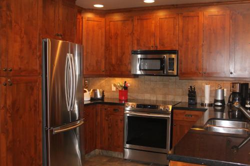 a kitchen with wooden cabinets and a stainless steel refrigerator at Woodhaven # 8 in Sun Peaks in Sun Peaks