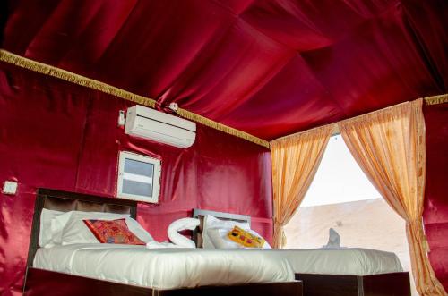 a red room with two beds and a window at Arena Desert Camp & Adventurers in Wadi Rum
