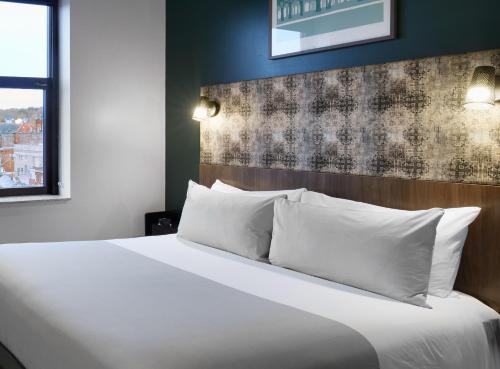 a bedroom with a large bed with white pillows at TRYP by Wyndham Pittsburgh/Lawrenceville in Pittsburgh