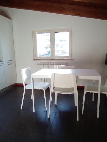 a white dining room table with white chairs and a window at PESCARA HOME anto in Pescara