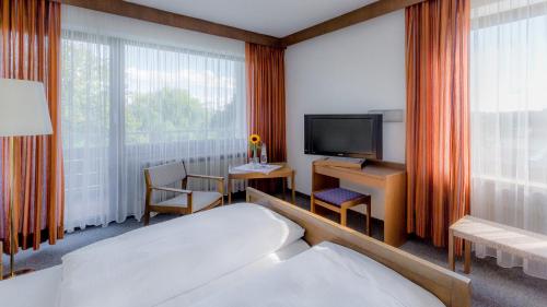 a hotel room with a bed, desk and television at Hotel Parsberg in Puchheim