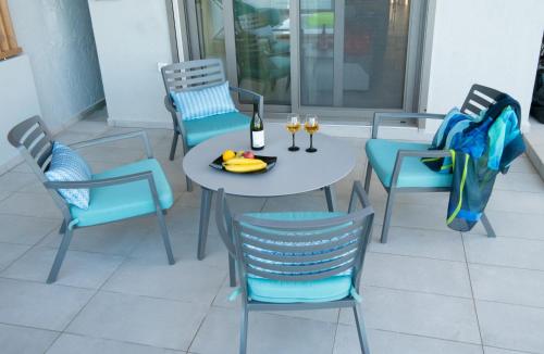 a table and chairs with a bottle and glasses of wine at LENICO Seafront Villa in Agia Pelagia
