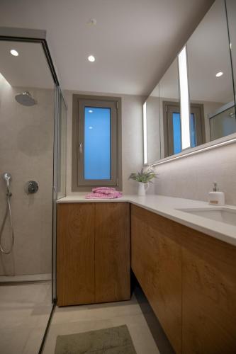 a bathroom with a sink and a shower and a mirror at LENICO Seafront Villa in Agia Pelagia