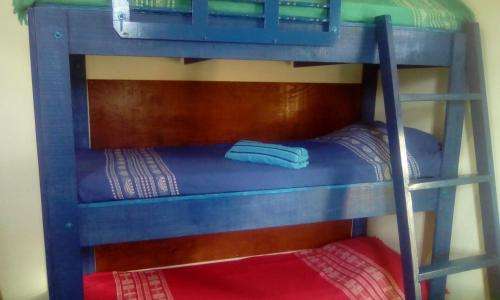 a bunk bed with a ladder and a red pillow at Apartamento Da Praça in Arraial do Cabo