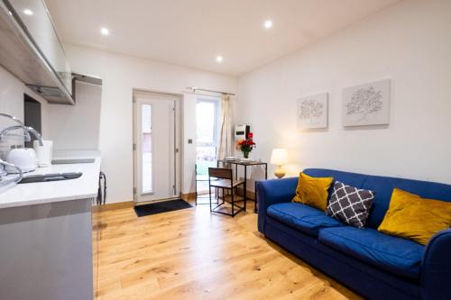 a living room with a blue couch and a kitchen at Three Tuns Apartments - Ash in Pettistree