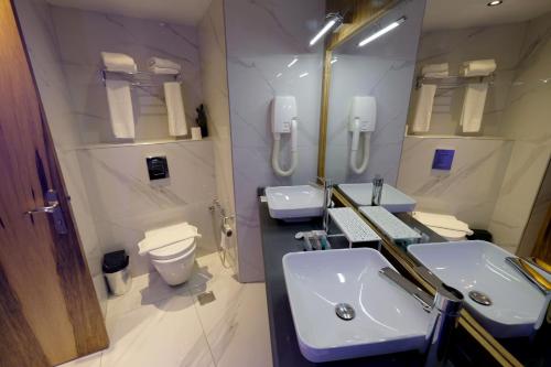 a bathroom with two sinks and a mirror and a toilet at Royal Court Hotel in Ramallah