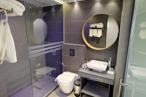 a bathroom with a toilet and a mirror at Royal Court Hotel in Ramallah