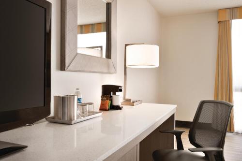 a room with a desk with a television and a chair at Radisson Hotel Lenexa Overland Park in Lenexa