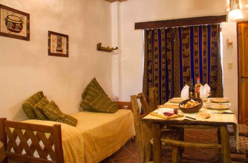 a room with a table and a bed and a table and chairs at Cabañas Tilcara Mia in Tilcara