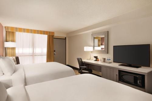 a hotel room with two beds and a flat screen tv at Radisson Hotel Lenexa Overland Park in Lenexa