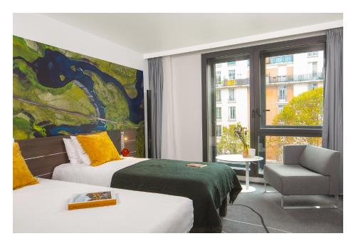 a bedroom with two beds and a chair and a window at Novotel Paris Porte Versailles in Paris