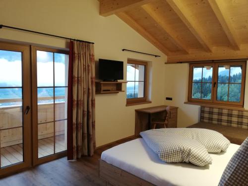 a bedroom with a bed and a tv and windows at Gasthaus Goglhof in Fügenberg