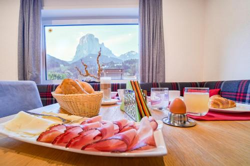 a table with a plate of meat and bread on it at Kedul Lodge in Santa Cristina in Val Gardena