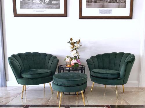 two green chairs and a table in a room at Commercial Motel in Hay