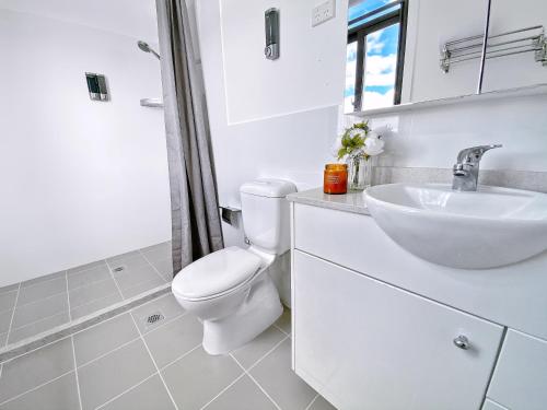 a white bathroom with a toilet and a sink at Commercial Motel in Hay