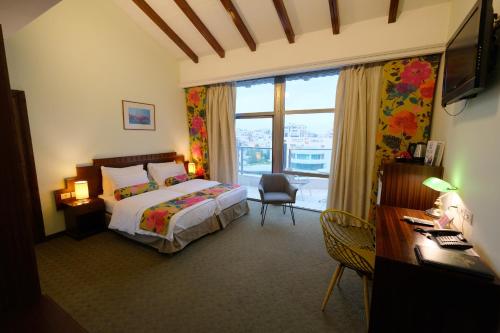 a bedroom with a bed and a desk and a window at Royal Court Hotel in Ramallah