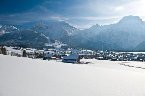 a town in the snow with mountains in the background at Genuss - und Vitalhotel Moisl in Abtenau