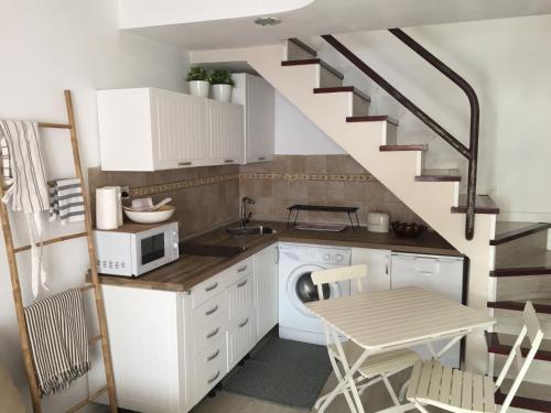 a kitchen with white cabinets and a staircase with a table at ETNICAN in San Bartolomé de Tirajana