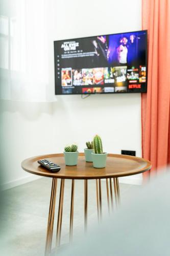 a table with two plants and a tv on a wall at City Apartments Hannover in Hannover