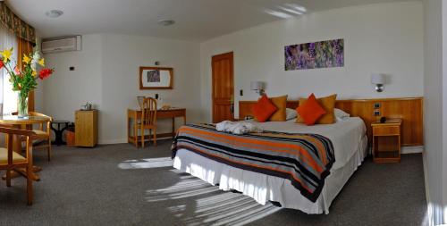 a bedroom with a bed and a table and a desk at Termas El Corazon in San Esteban
