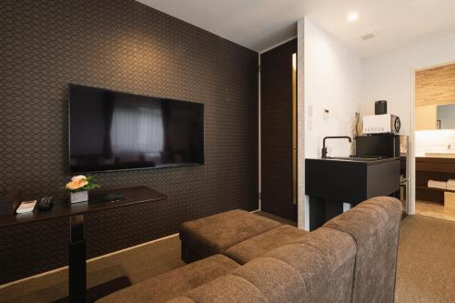 a living room with a couch and a flat screen tv at GRAND BASE Nagasaki Ekimae in Nagasaki