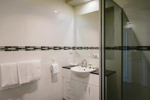 a white bathroom with a sink and a shower at Fairways Resort in Rosebud