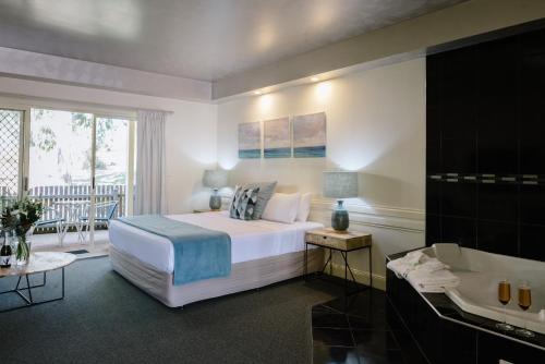 a bedroom with a bed and a bath room with a tub at Fairways Resort in Rosebud